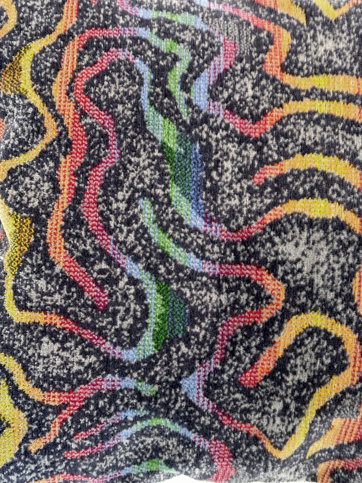 Detail of moquette cushion in grey with rainbow pattern