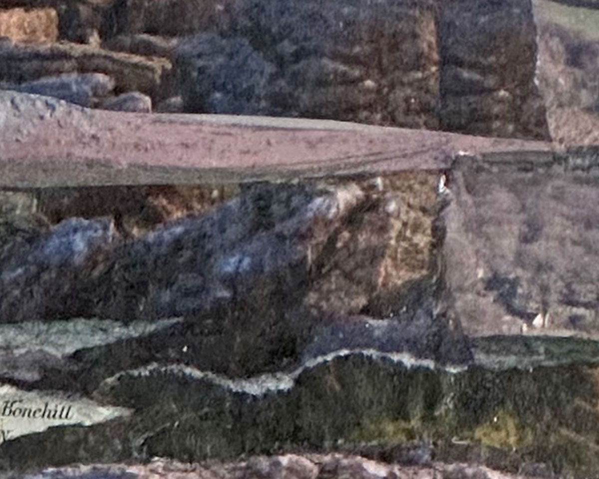 Close-up of a stone wall with a bench and natural rock background