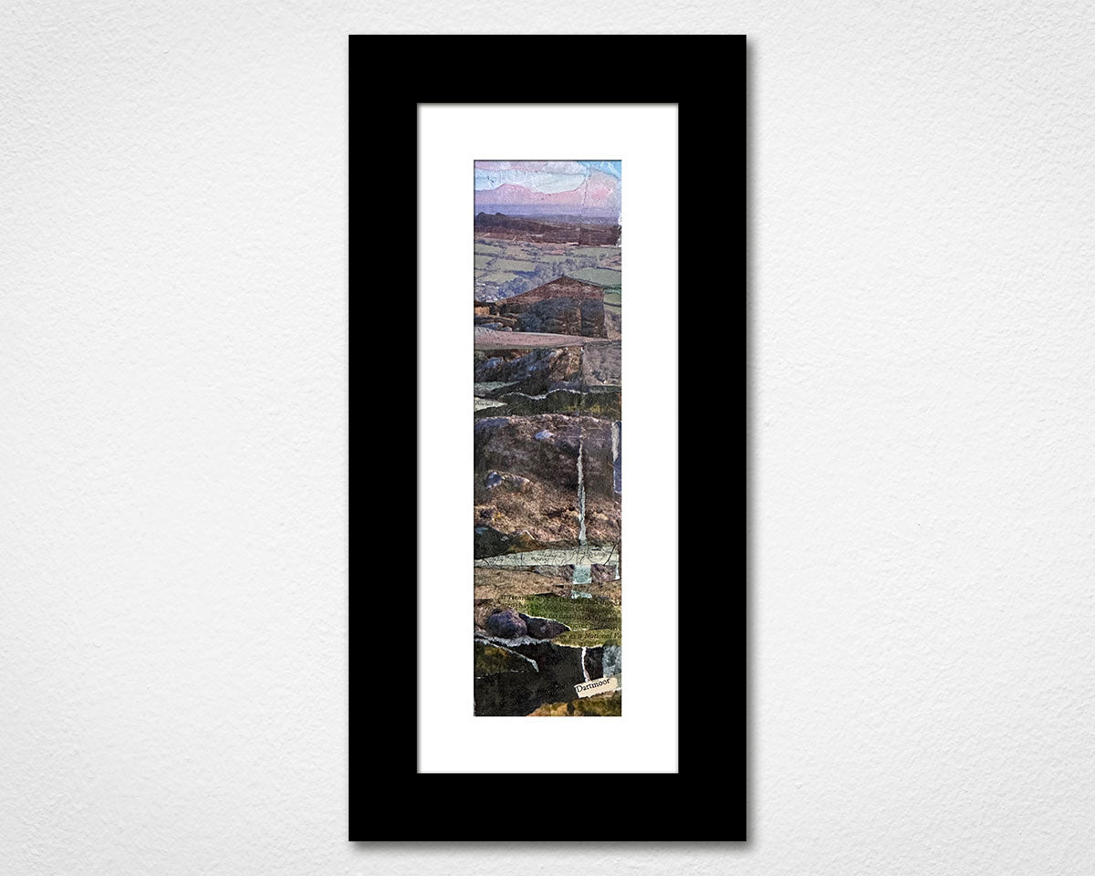 Framed artwork of a landscape with mountains and a lake on a white wall.