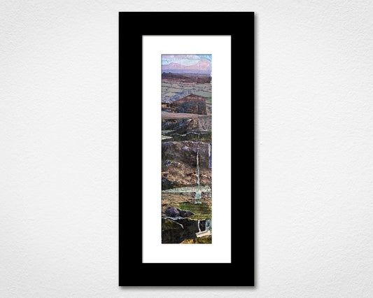 Framed artwork of a landscape with mountains and a lake on a white wall.