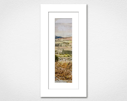 Framed landscape print of a field with trees on a white wall