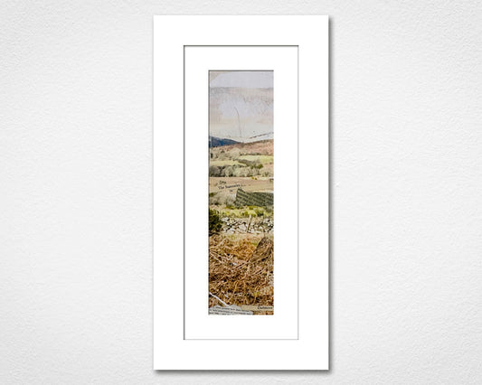 Framed landscape print of a field with trees on a white wall