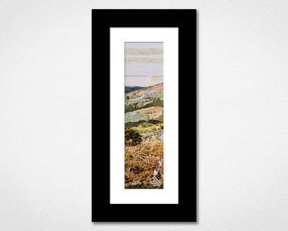 Framed landscape print of a scenic view with a black frame on a white wall.