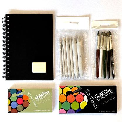 The Pastels Kit Box containing art supplies including a black notebook, pastels, and drawing tools on a white background