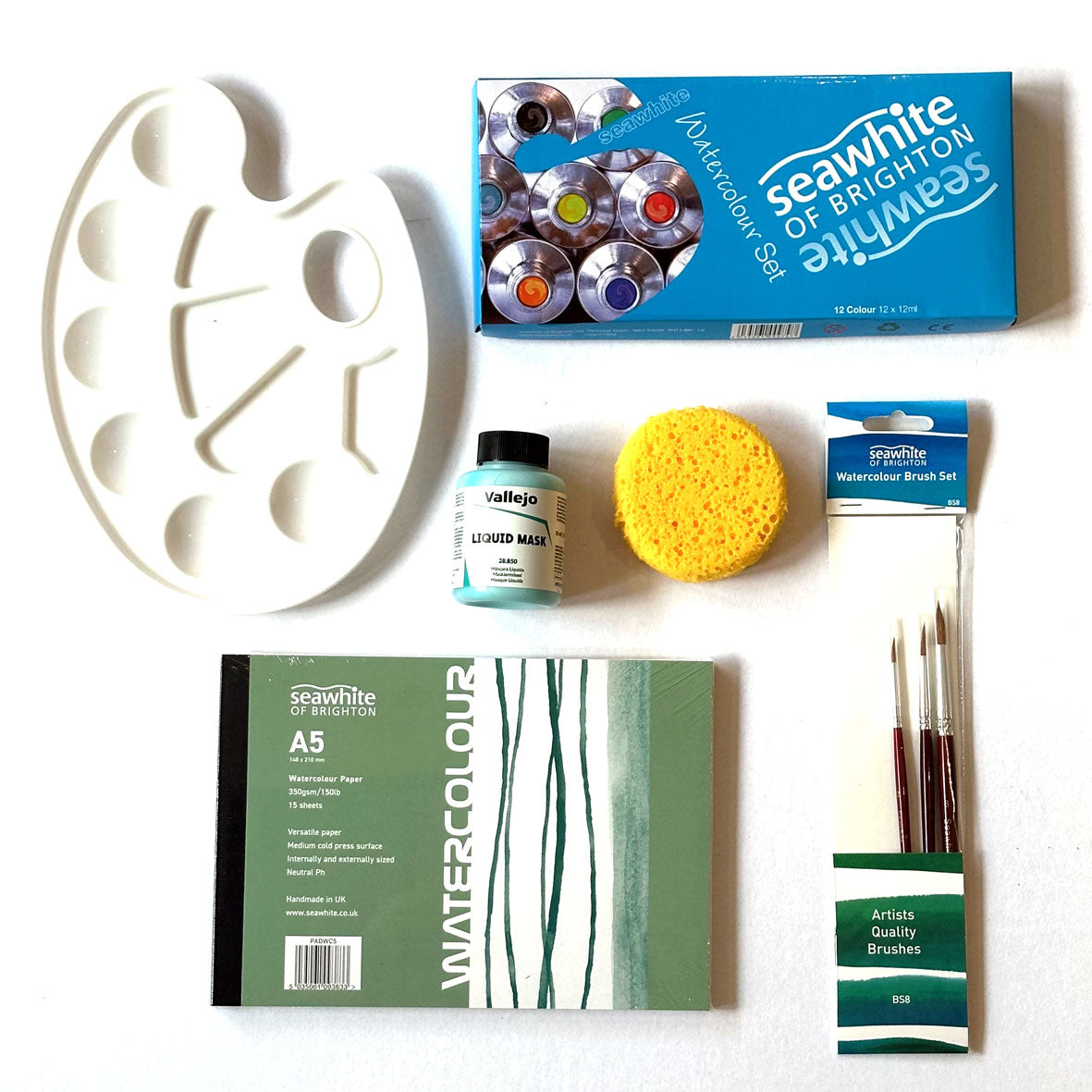 The Watercolour Kit Box containing art supplies including a paint palette, watercolor paper, brushes, and a sponge on a white background.
